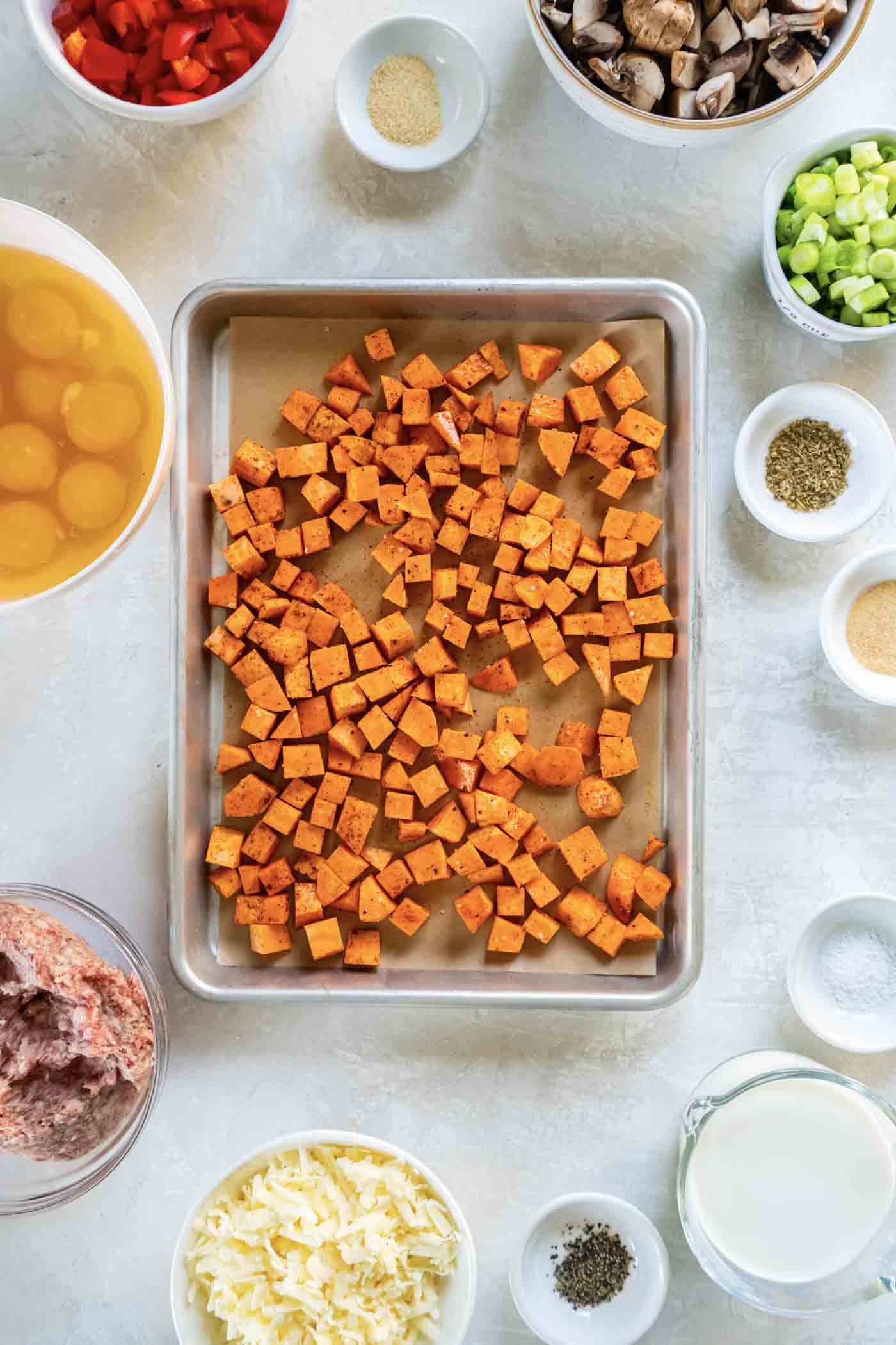 The BEST Breakfast Casserole with sausage, veggies and cheese! This recipe is make-ahead friendly, I like to prep it the night before and refrigerate overnight, then bake in the morning for an easy holiday breakfast! Cubed seasoned sweet potatoes on parchment paper-lined baking sheet.